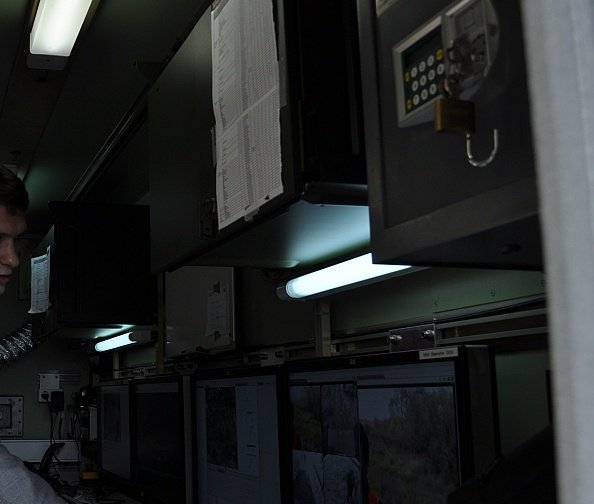 A bank of monitors and control panels inside a vehicle-mounted operations console.